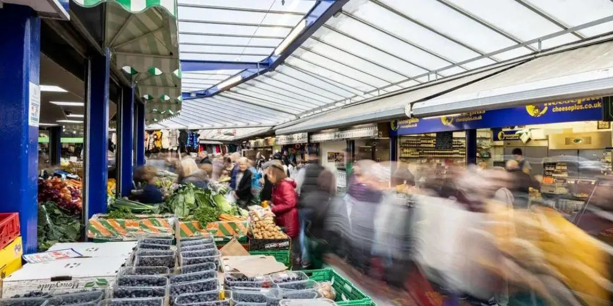 A bustling Bury Market with tubs of berries and vegetables on show.