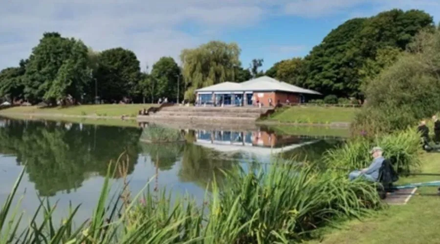 a photo of the lido at Clarence Park, with people fishing, blue skies with a scattering of cloud