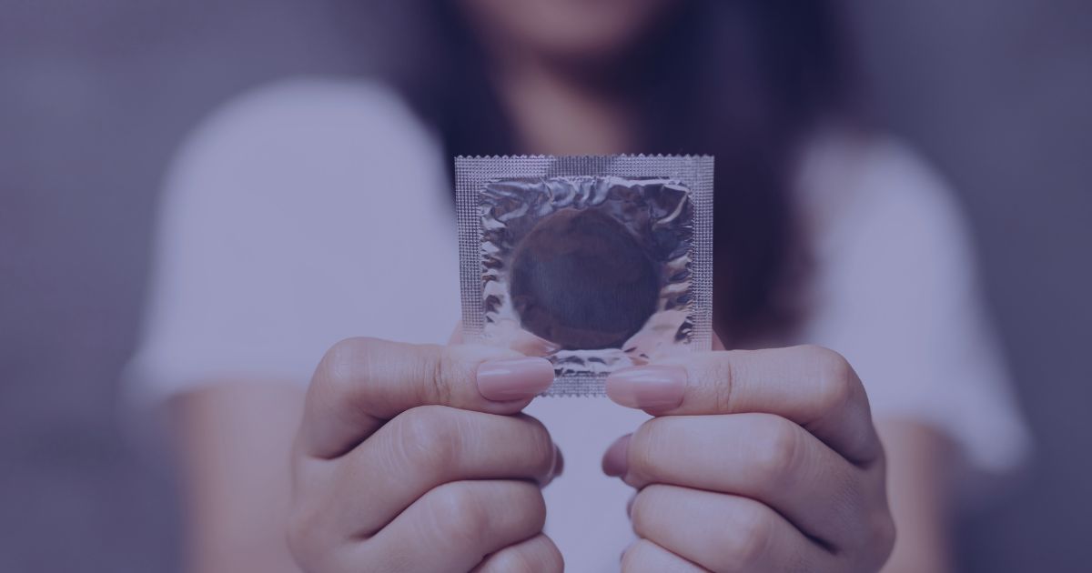 Woman holding an unopened condom packet with both hands.
