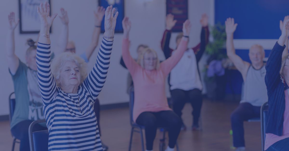 a group of males and females undertaking gentle chair based exercises