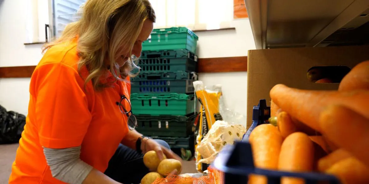 a lady preparing and sorting food items such as potatoes and carrots ready for distributing at the food bank.