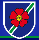 Greenmount primary school logo of a red flower in a white shield on a blue background
