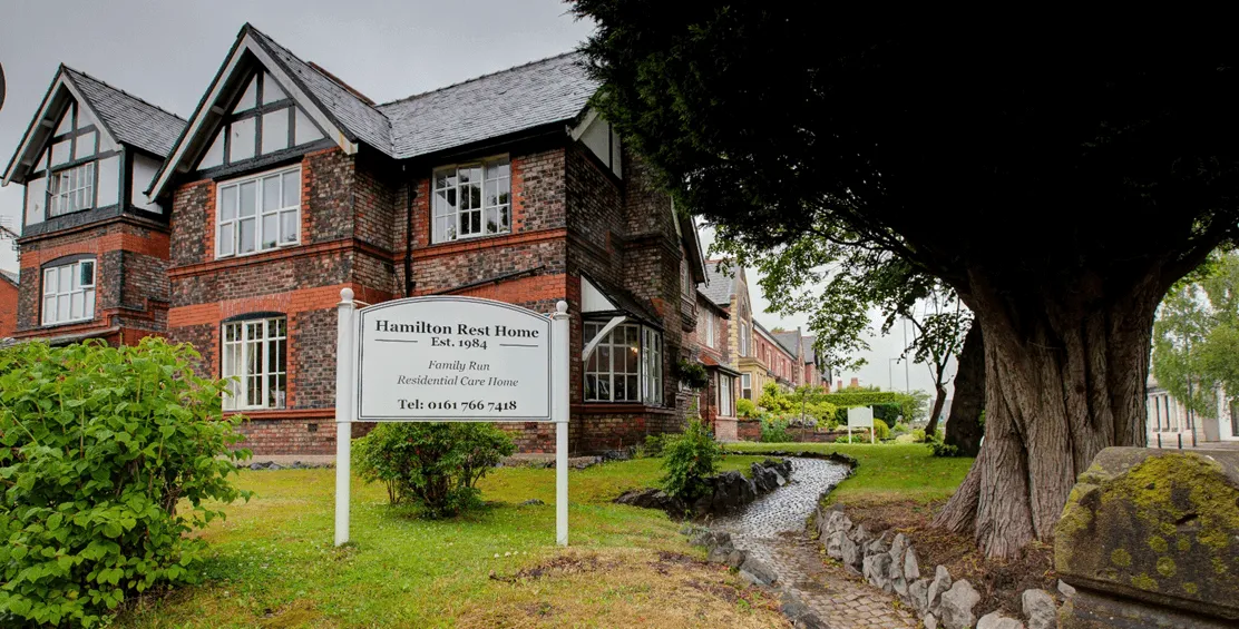 a building with a white sign displaying the words hamilton rest home