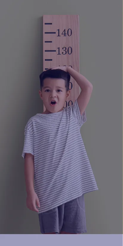 a child standing against a large measuring stick to measure how tall he is