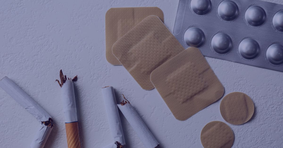 a collection of nicotine replacement options including patches and tablets on a table next to snapped cigarettes