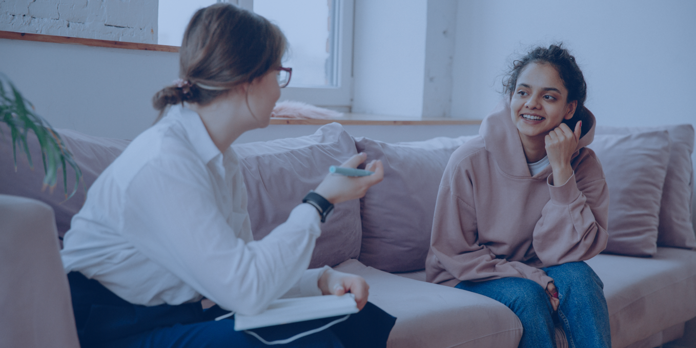 Two women sat on a sofa talking