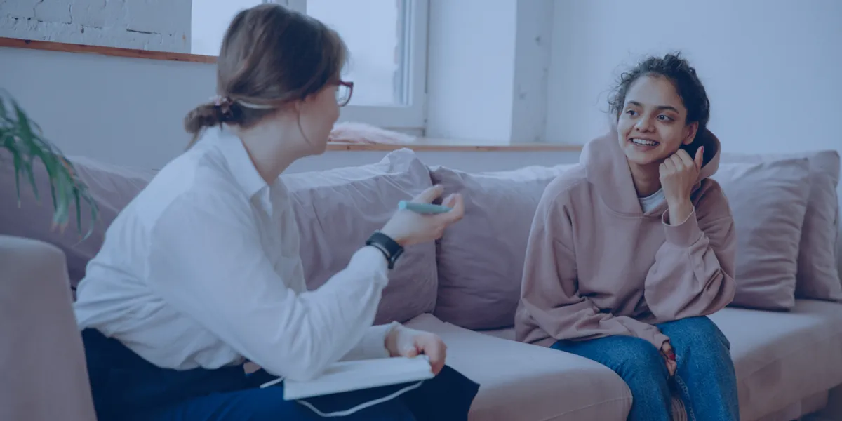Two women sat on a sofa talking