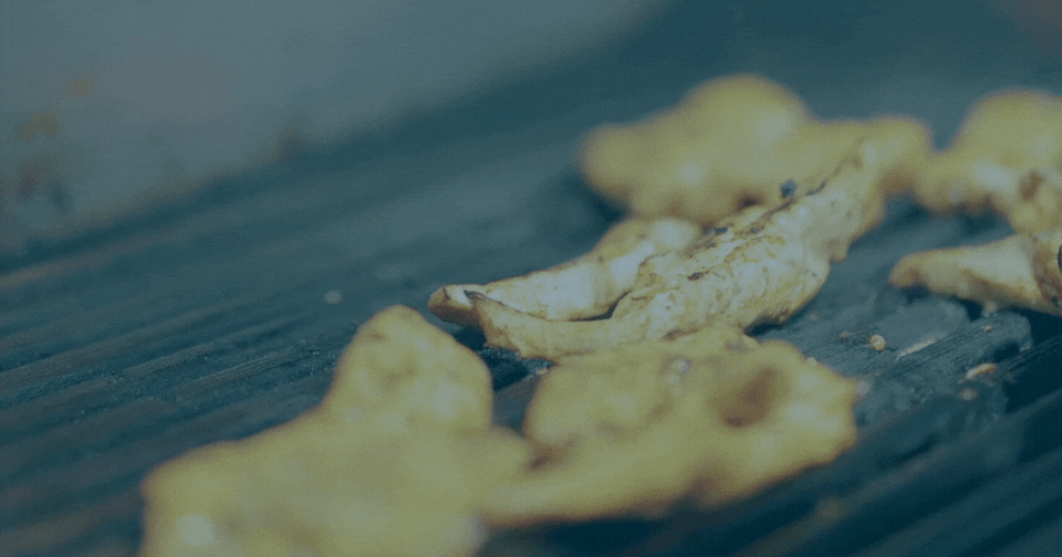 chicken being cooked on a hot open grill
