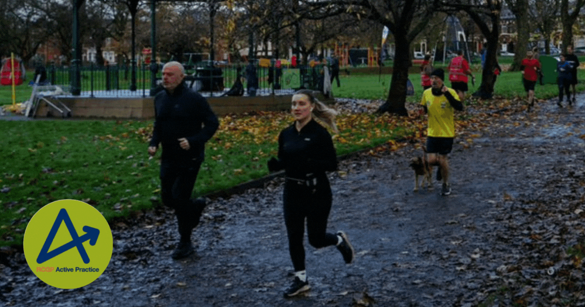 a mix of both men and women jogging through a park, including one man with his dog
