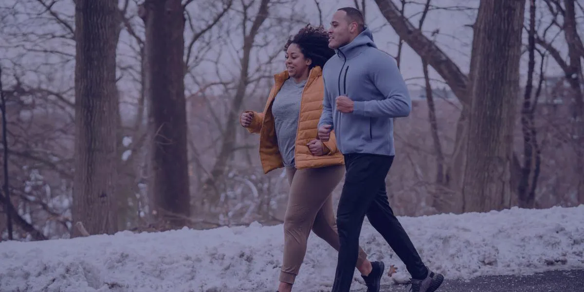 a man and a women jogging down a snowy path